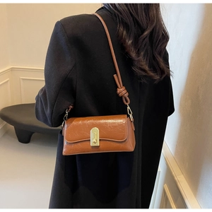 Détail d'un sac bandoulière marron vintage avec boucle dorée et lanière à nœuds chic