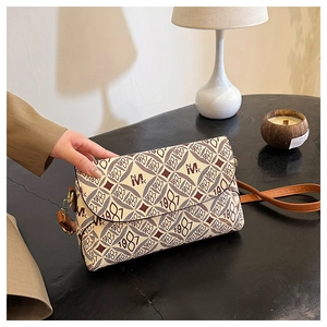 Dettaglio borsa a tracolla beige elegante con stampa monogramma rossa e chiusura in metallo