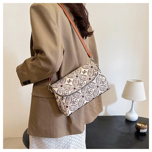 Dettaglio della borsa a tracolla con motivo monogramma beige e cinturino in pelle marrone