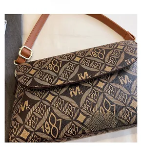 Dettaglio della borsa a tracolla marrone con motivo monogramma e fibbia in metallo dorato