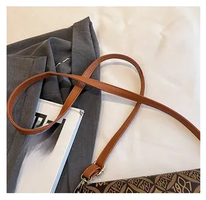 Dettaglio della tracolla in pelle marrone e stampa vintage sulla borsa a tracolla