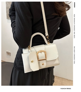 Detail of white square crossbody bag with oversized gold buckle and mini pouch accessory