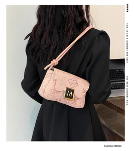 Rear view of model wearing pink monogram shoulder bag with gold metal M-shaped buckle
