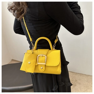 Detail of yellow pebbled leather crossbody bag with square buckle and mini coin purse