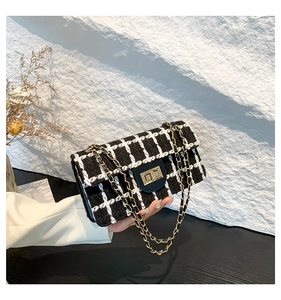 Détail de la texture en tweed noir et blanc avec bandoulière en chaîne dorée du sac