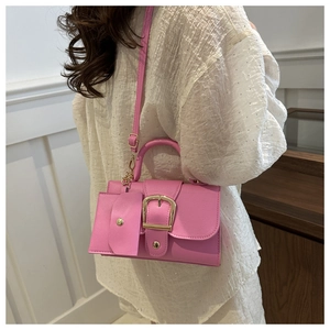 Pink crossbody bag with pebble leather texture and gold buckle detail on a model