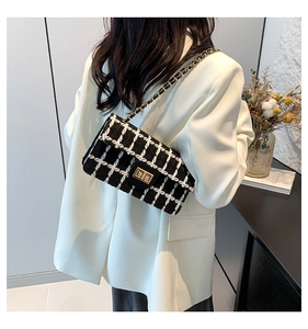 Détail du sac bandoulière en tweed noir et blanc avec chaîne dorée sur un mannequin