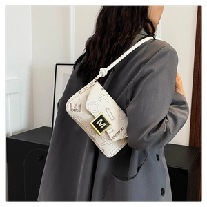 Detail of white monogrammed crossbody bag with gold-tone hardware and knot strap