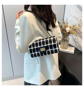 Sac bandoulière classique en tweed noir et blanc avec chaîne dorée sur blazer blanc