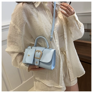Detail of light blue crossbody bag with lychee texture and gold buckle decoration