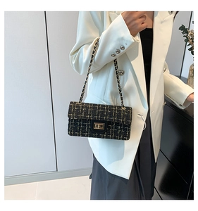 Détail d'un sac bandoulière en tweed noir avec chaîne dorée porté sur une tenue