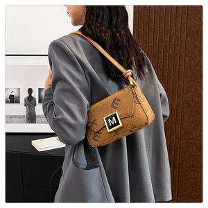 Detail of vintage brown shoulder bag with geometric print and gold M metal clasp