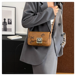 Lifestyle shot of a brown monogrammed crossbody bag paired with a grey professional blazer