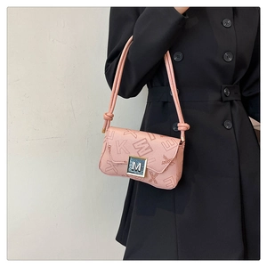 Pink shoulder bag detail showing stylish letter print and metallic M buckle on black suit