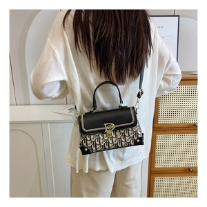 Détail d'un sac bandoulière vintage en toile monogrammée avec boucle en D et bandoulière