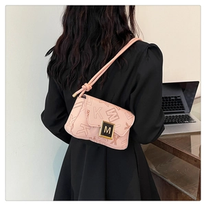 Detailed view of pink shoulder bag with monogram print and gold M logo buckle on model