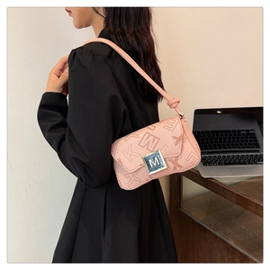 Close-up of pink underarm bag with letter pattern and metallic M-shaped buckle detail