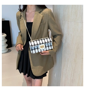 Sac en tweed à carreaux noir et blanc avec bandoulière dorée porté par un mannequin