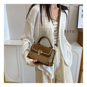 Détail du sac bandoulière vintage à motifs avec boucle dorée et lanière en cuir sur modèle