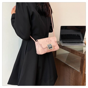 Detail view of pink leather crossbody bag with letter patterns and silver M buckle