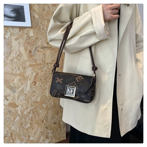 Detail of vintage brown leather underarm bag with monogram print and silver M buckle