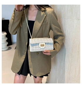 Détail d'un sac à bandoulière en tweed avec chaîne dorée et boucle porté par un modèle