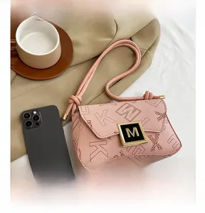 Detailed close-up of pink underarm bag with gold M buckle and letter K pattern