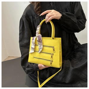 Fashionable bright yellow crossbody bag with zipper detail and decorative silk scarf