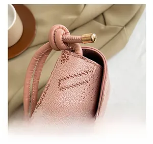 Detailed close-up of pink pebbled leather bag with gold hardware and knotted strap