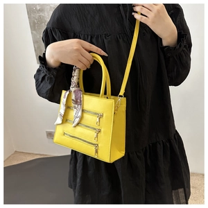 Close-up of yellow crossbody bag with zipper accents and scarf-wrapped handle on a model