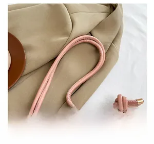 Close-up of knotted leather shoulder strap with gold metal ends on printed crossbody bag