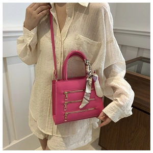 Detail of rose red crossbody bag with decorative zippers and floral silk scarf handle