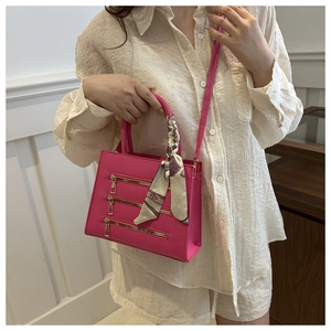 Detail of fuchsia leather handbag with gold zippers and decorative floral silk scarf