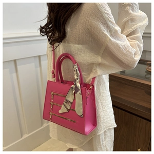 Detail of hot pink handbag with gold zippers and silk scarf wrapped around handle