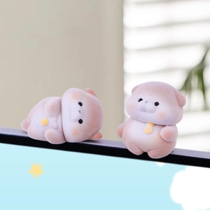 Cute flocked otter figurines placed as decor on a computer monitor screen top