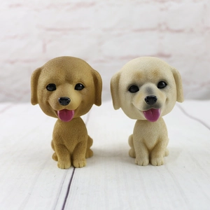 Detail view of brown and cream nodding dog figurines for car dashboard decoration