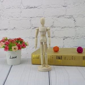 Artistic wooden mannequin with flexible joints standing on a base against a cozy bookshelf