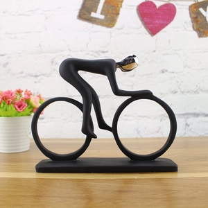 Modern abstract cyclist sculpture in matte black and chrome on a wooden tabletop