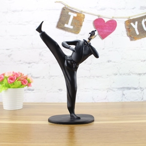 Detail of matte black martial arts resin sculpture with silver head in a side kick pose