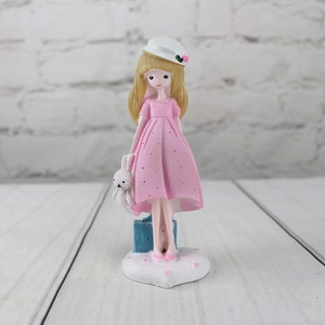 Detail of cute resin girl figurine with pink dress and white rabbit in hand