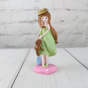 Detail of cute resin girl figurine with teddy bear on a pink polka dot heart base