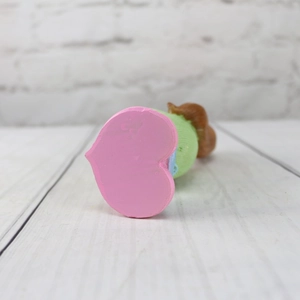 Detail shot of a cute cartoon girl figurine featuring a pink heart-shaped base and resin body