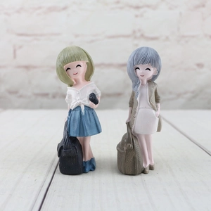 Detailed close-up of two cute resin girl figurines in stylish outfits for home decor
