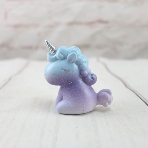 Primer plano de figurita de unicornio brillante azul-púrpura con cuerno espiral plateado