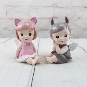 Detailed view of resin angel and devil baby figurines for cake toppers or gifts