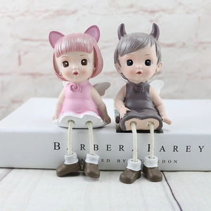 Detail of resin angel dolls with dangling rope legs on a decorative book stand
