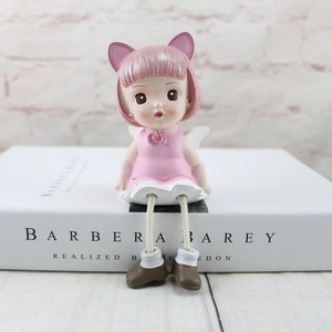 Pink resin angel doll figurine with dangled legs sitting on books for home decor