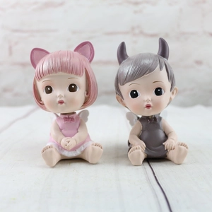 Close-up of resin angel and devil figurines with wings on wooden texture