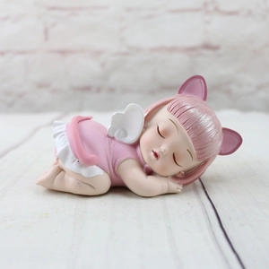 Detail of a pink resin sleeping angel doll with cat ears and white wings for cake decor