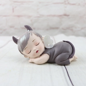 Close-up of a sleeping resin baby demon figurine with detailed gray wings and horns